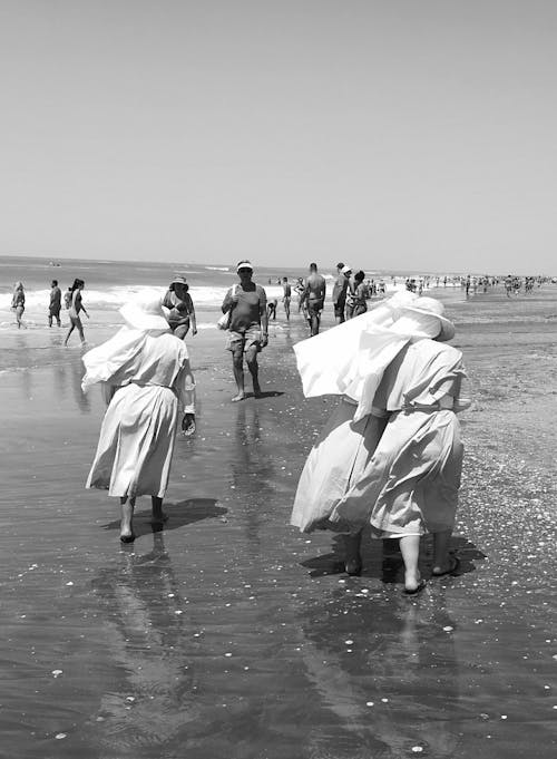 Grayscale Photo of People Walking at the Beach 