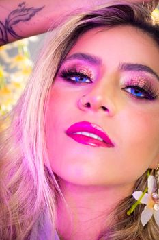 Striking portrait of a woman with glittery eye makeup and pink lips under vibrant lighting.
