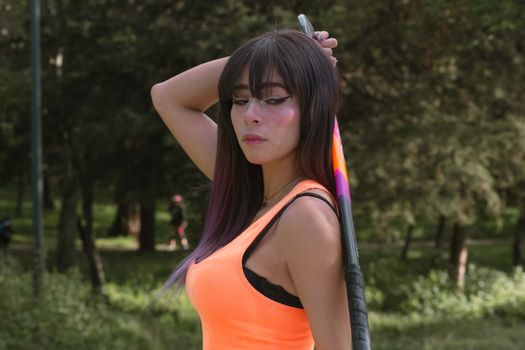 pretty and sexy sporty millennial girl posing dressed in a field hockey outfit with an orange t-shirt blue shorts and orange socks