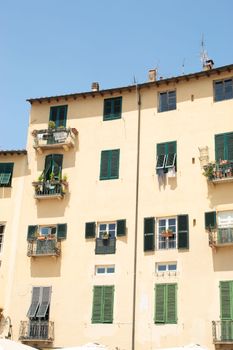 A beautiful old building facade with green shutters and balconies in bright daylight.