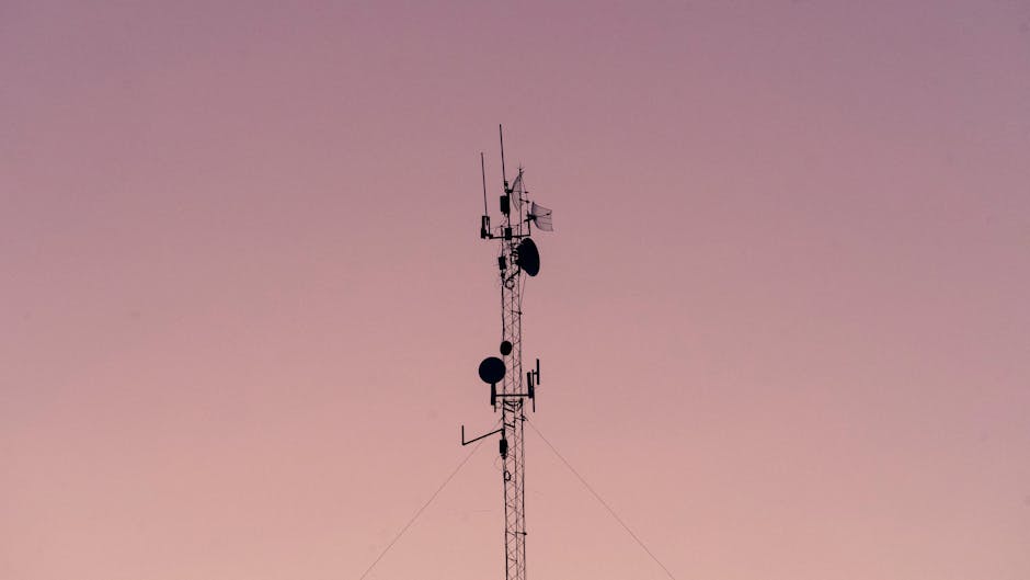 A tall telecommunication tower silhouetted against a clear dusk sky.