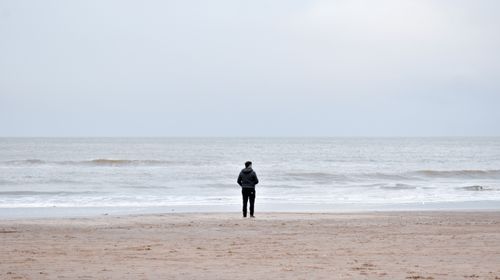 Free A person in a jacket stands alone looking at the ocean on Santa Teresita Beach. Stock Photo