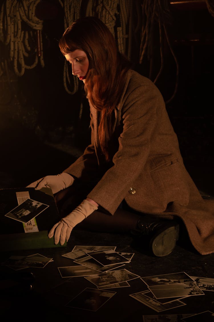 Woman In Brown Long Sleeve Coat Looking At Old Pictures