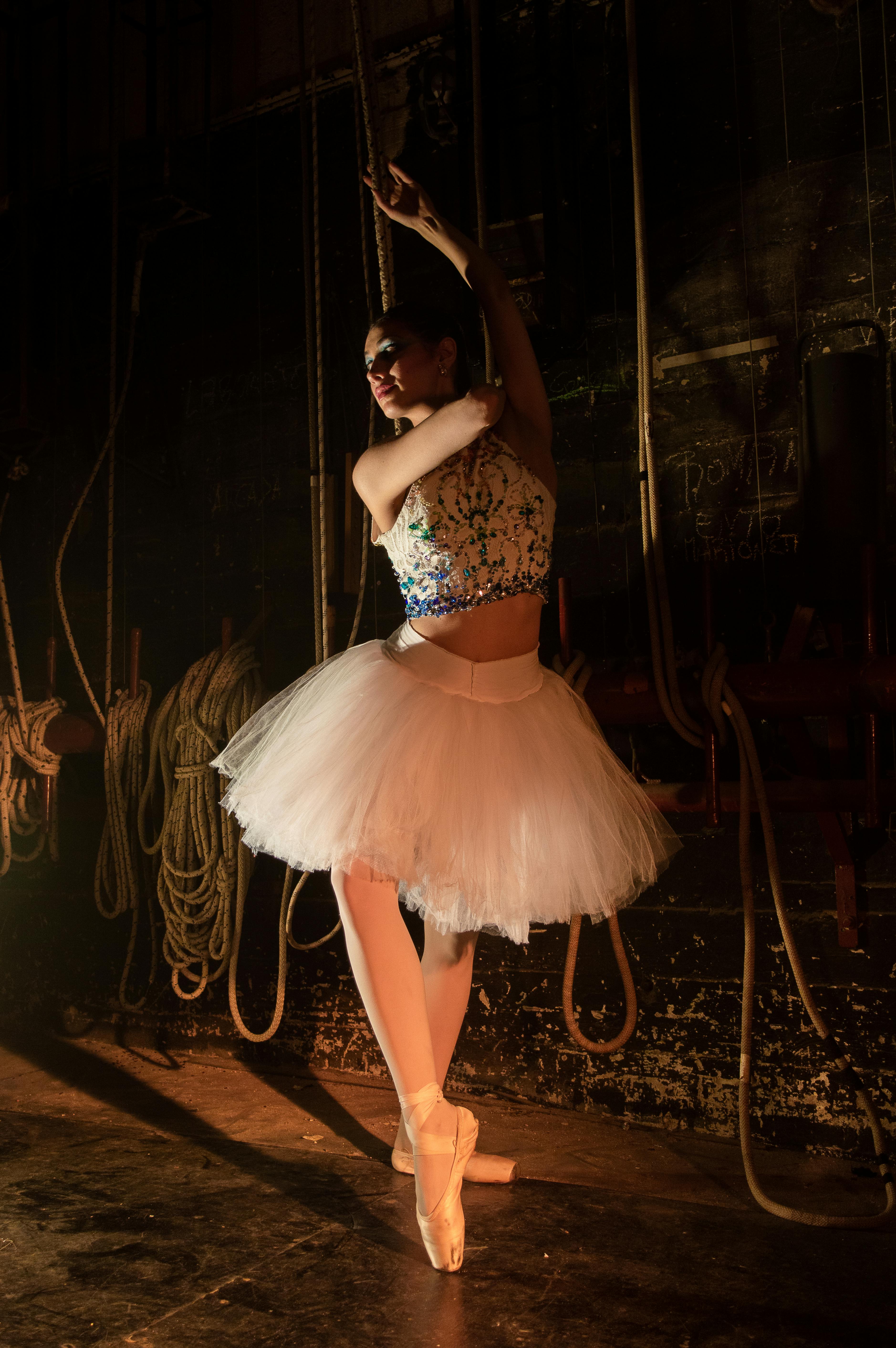 Free Ballerina posing gracefully in a dimly-lit backstage setting at a theater. Stock Photo