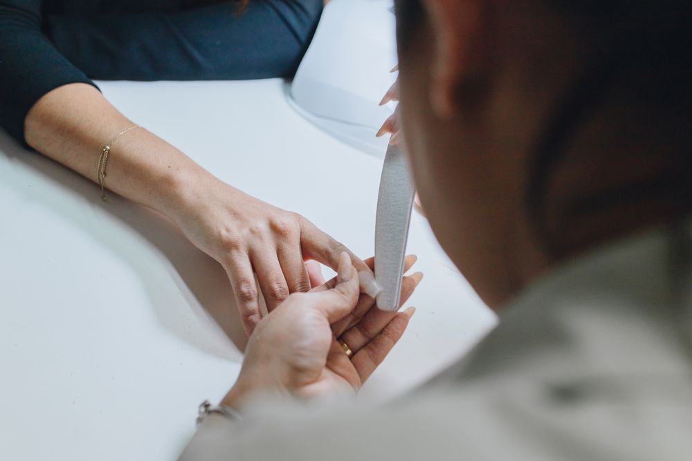 Nail technician filing stiletto-shaped nails during a professional manicure