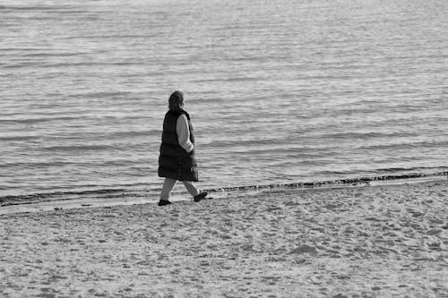 Free A Woman Walking Along the Shore Stock Photo