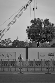 A construction worker walks in front of a crane at a city construction site.