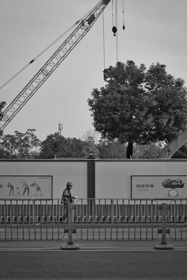 Monochrome Photo Of Construction Worker Walking On A Sidewalk 