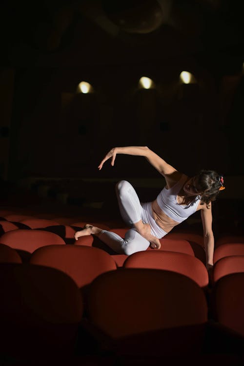 A Woman Dancing While Sitting on the Theater Chairs