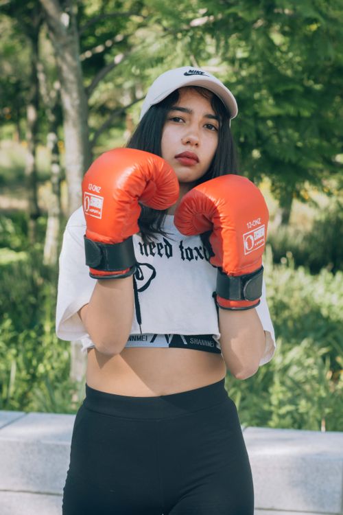 Free Confident young woman in boxing gloves posing outdoors, showcasing strength and style. Stock Photo