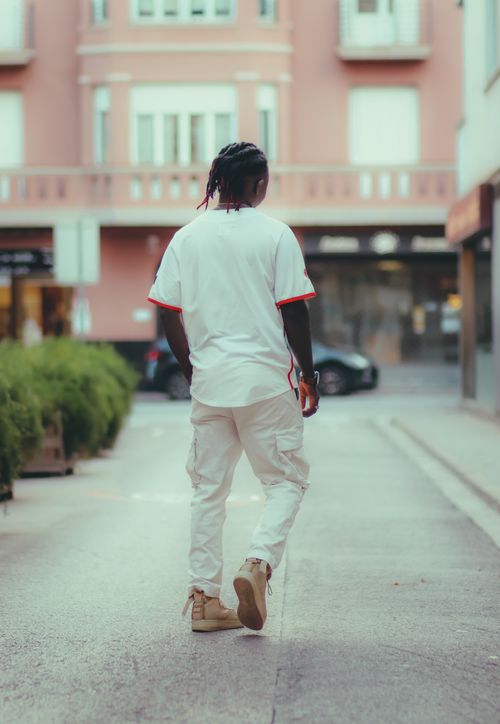 Free A stylish man in white clothing walking through an urban street during the day, showcasing street fashion. Stock Photo