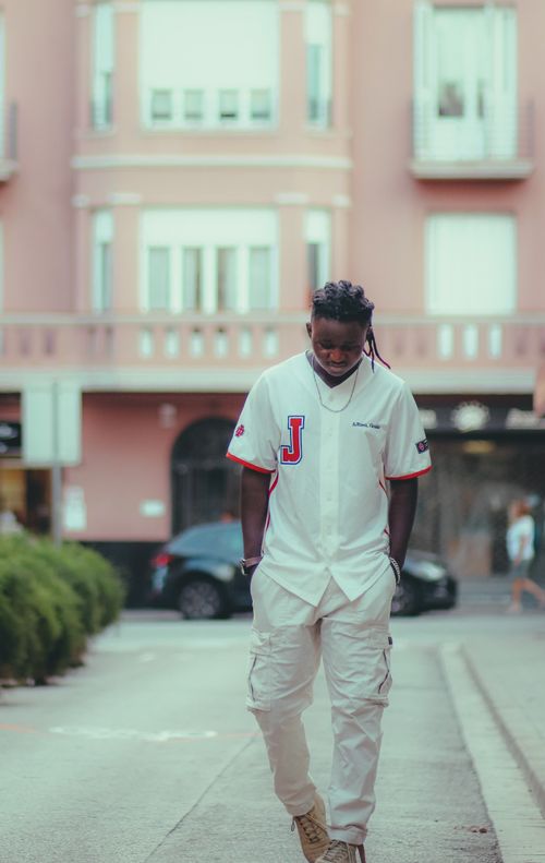 Free Casual urban scene of a young man in white clothing walking on a street. Stock Photo