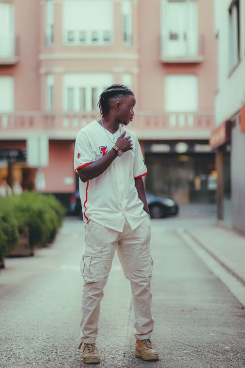 Free Young man in fashionable attire poses in an urban street setting, showcasing modern street style. Stock Photo