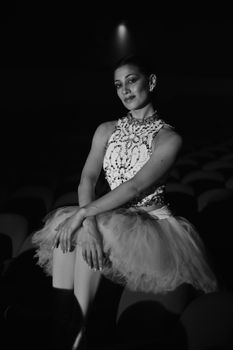 Black and white portrait of a graceful ballerina in a theater setting.