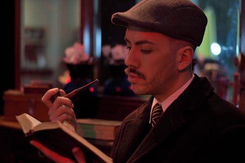 Man holding a Pipe while reading a Book 