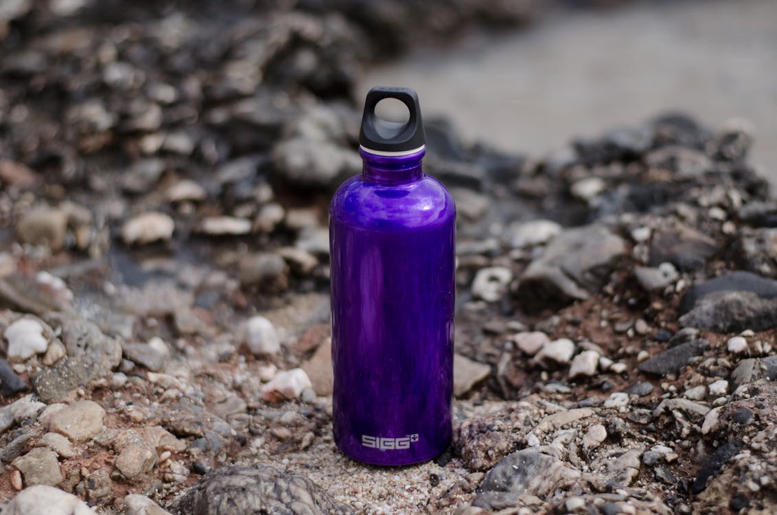 Eco-friendly reusable purple water bottle on ground