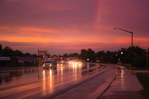 Free Vehicles navigate a rain-soaked highway at dusk under a vibrant sky. Stock Photo