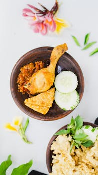 Top view of Indonesian chicken with sambal and fresh vegetables on a bowl.