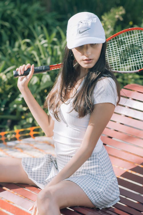 A Woman Holding a Tennis Racket While on a Bench