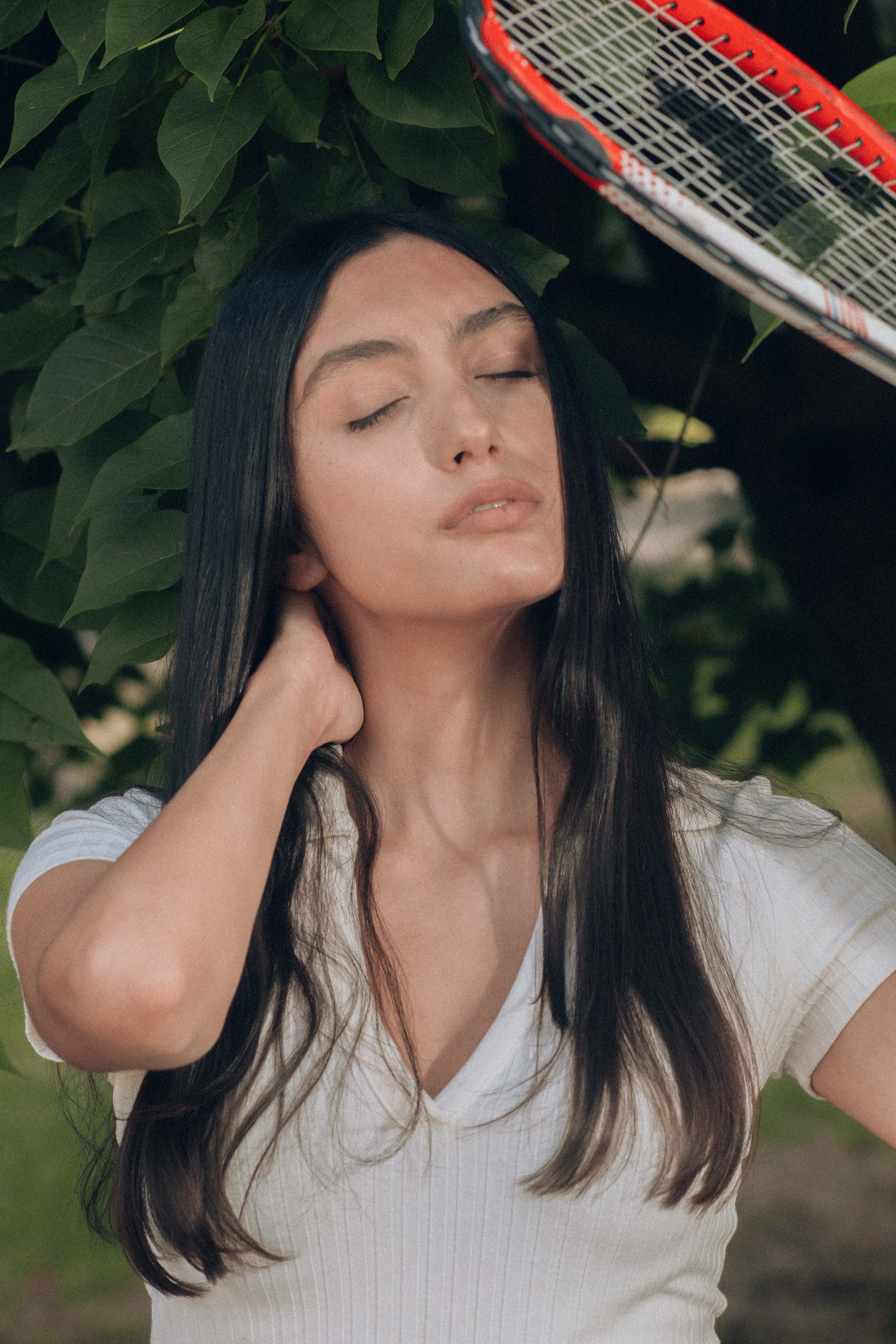 A peaceful portrait of a woman with long hair, eyes closed, outdoor setting.