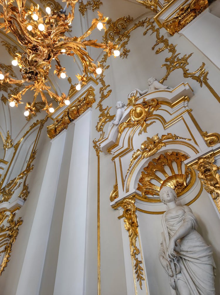 Sculpture And Golden Chandelier Over Wall