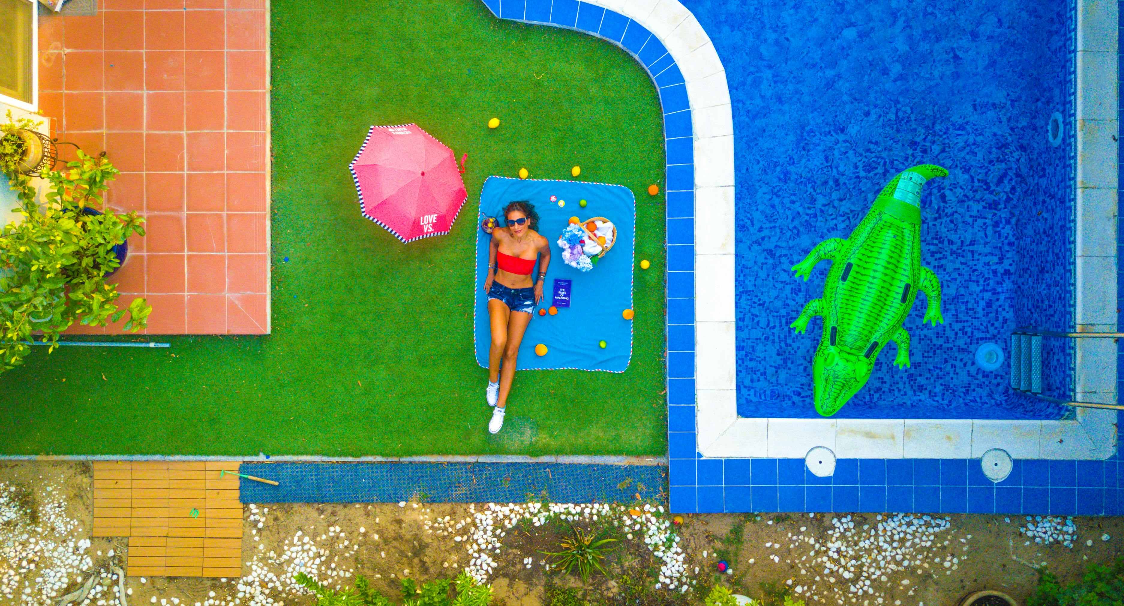 slim female tourist sunbathing near bright swimming pool on vacation