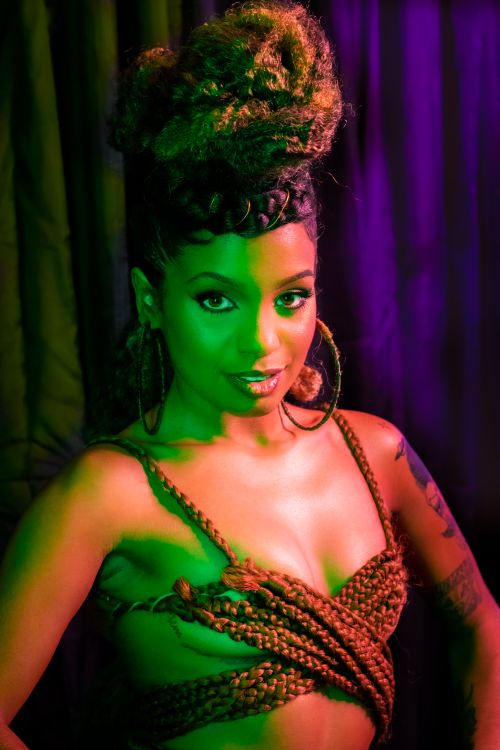Free A stylish woman with braids poses confidently with dramatic lighting onstage. Stock Photo