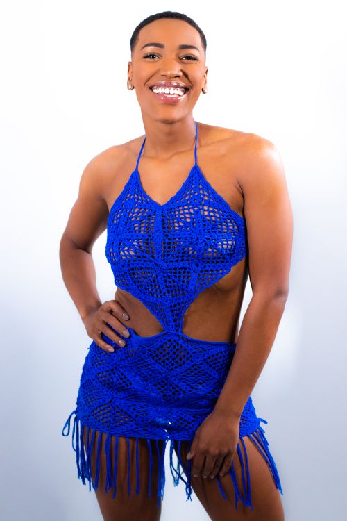Free Confident woman in a blue crochet dress smiling against a white background. Stock Photo