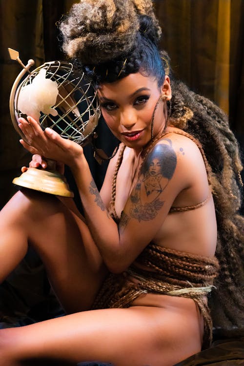 Nude Woman Wrapped in Her Braided Hair Posing with a Metal Globe