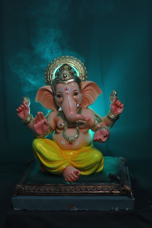Free A colorful Ganesha statue surrounded by mystical blue smoke, symbolizing Hindu spirituality. Stock Photo