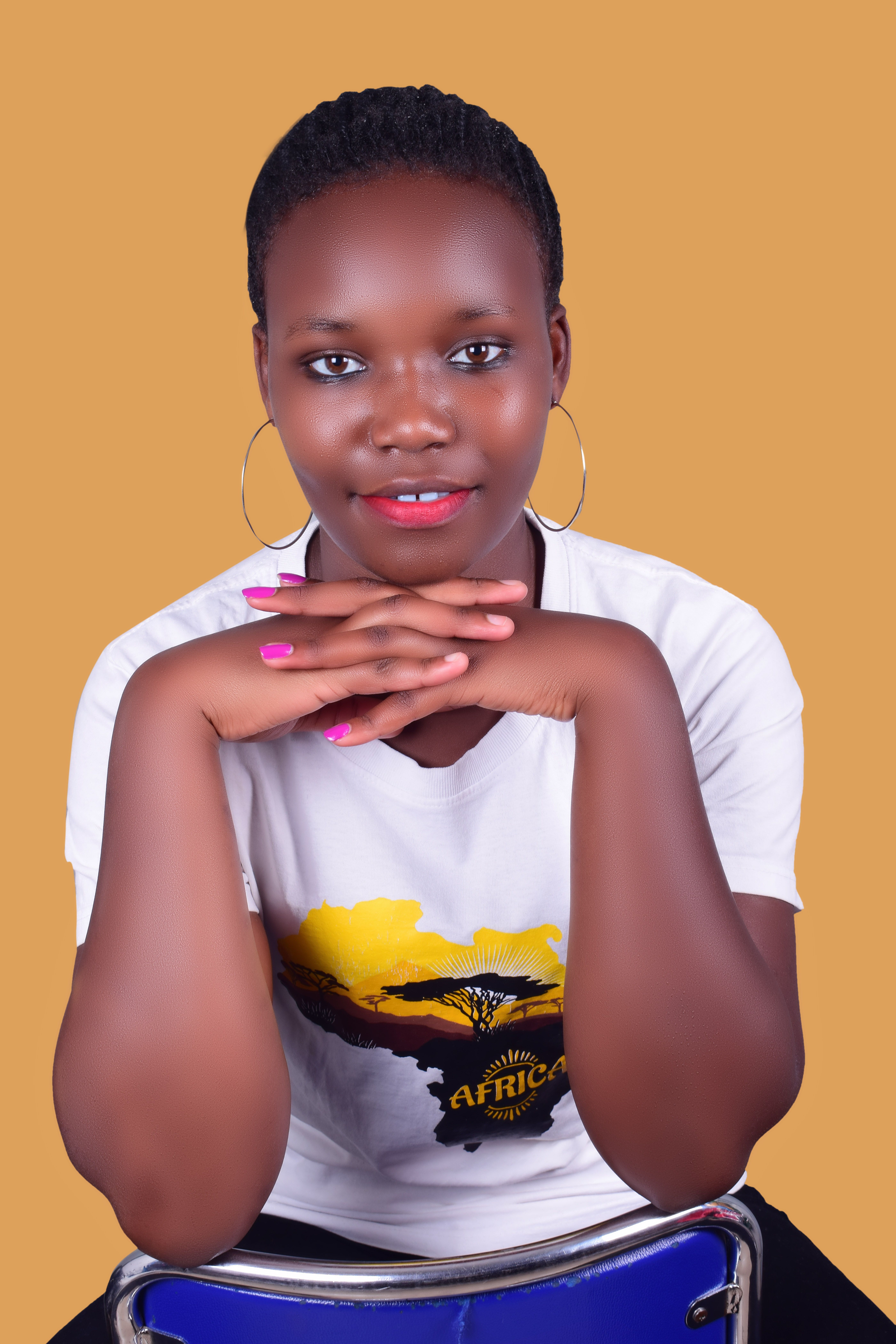 Smiling woman in a white shirt with African design, posing indoors.