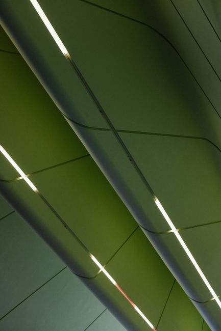 Abstract view of a green ceiling with linear lights creating geometric patterns.