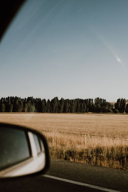 Serene countryside landscape view through a car window on a sunny day.
