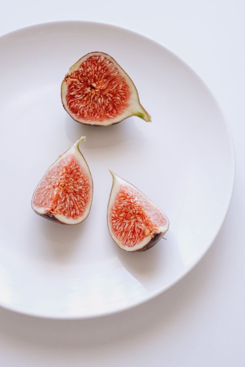 Free A close-up of fresh fig slices on a white plate, emphasizing healthy eating and simplicity. Stock Photo
