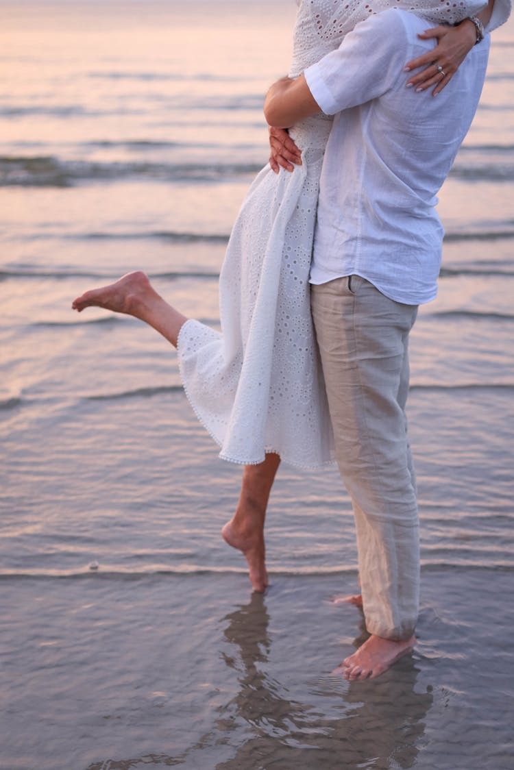 Couple In White Shirts Embracing On Seashore