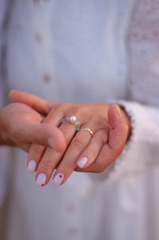 A close-up shot of hands with a pearl ring and stylish manicure, radiating elegance.