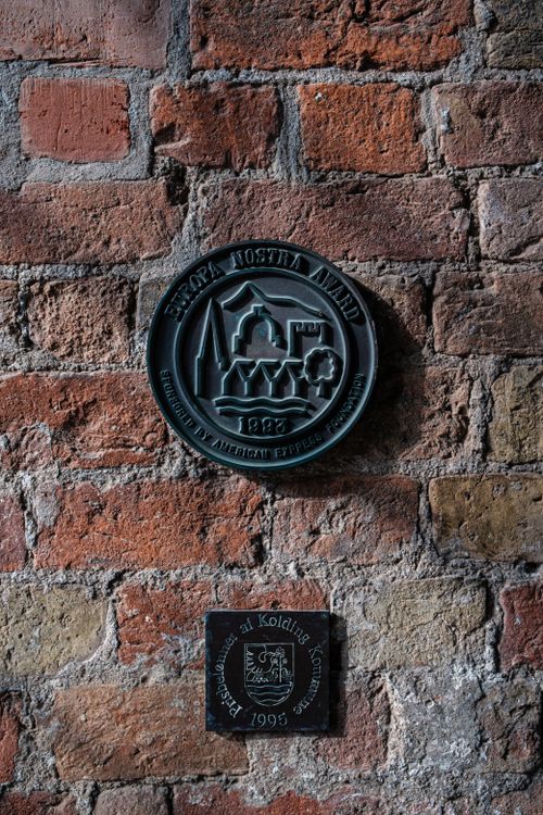 Free Close-up of a metal plaque on a weathered brick wall, showcasing a historic design. Stock Photo