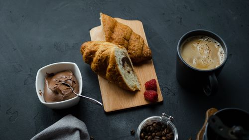 Free A cozy breakfast scene featuring croissants, raspberries, and a steaming cup of coffee. Stock Photo