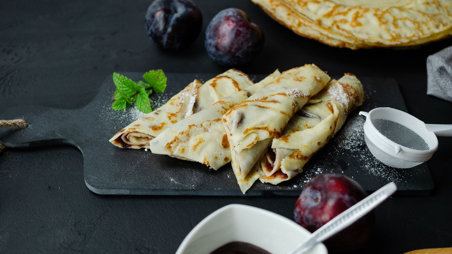 Stack of golden dessert crepes with berry filling