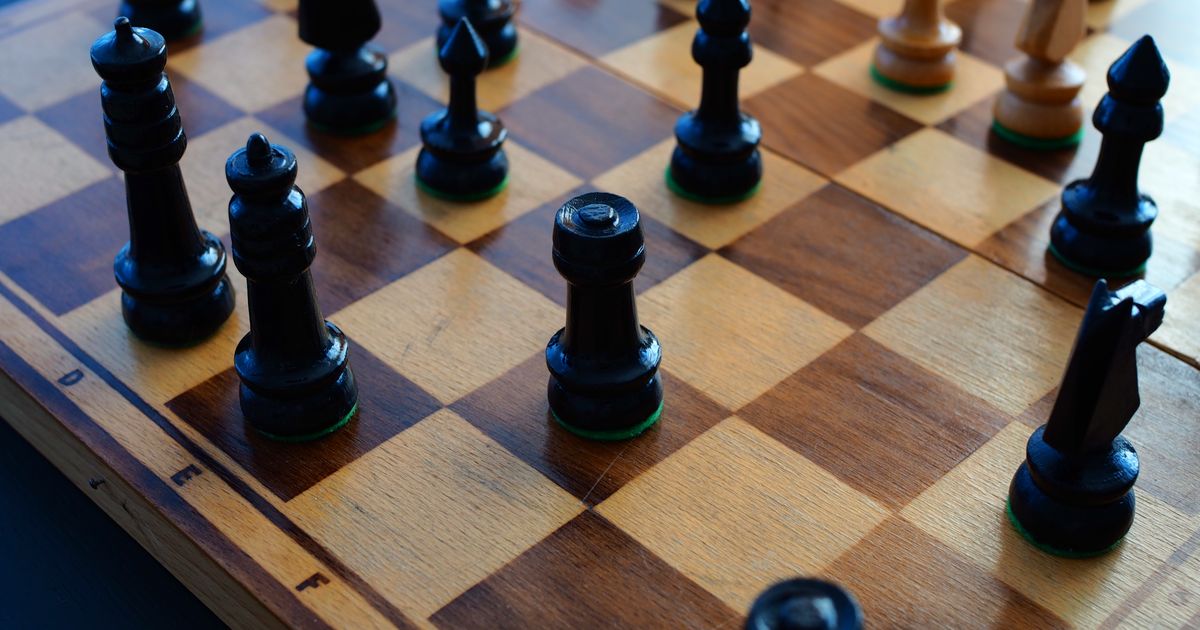 Chessboard with black and white pieces arranged mid-game on a wooden table