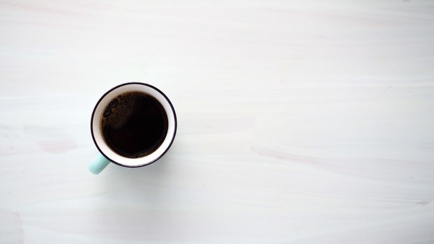 Elegant top view of a black coffee cup on a light wooden table with ample copyspace.