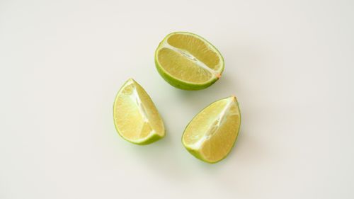 Free Minimalist image of fresh lime slices on a white backdrop, perfect for citrus-themed designs. Stock Photo