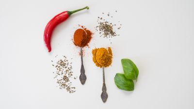 Chilli peppers and ground spices on a pale backdrop. Photo by Mateusz Feliksik on Pexels.