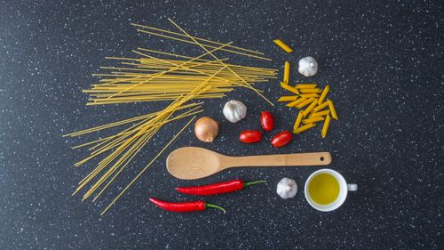 Free A collection of pasta ingredients including garlic, tomatoes, and olive oil on a dark background. Stock Photo