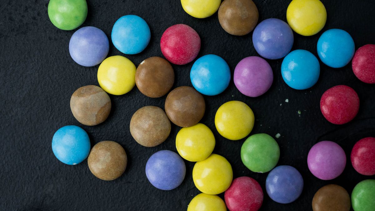 Close-up view of colorful candy-coated chocolates on dark background.