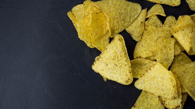 Close-up of crispy tortilla chips on a black surface, perfect for snack time.