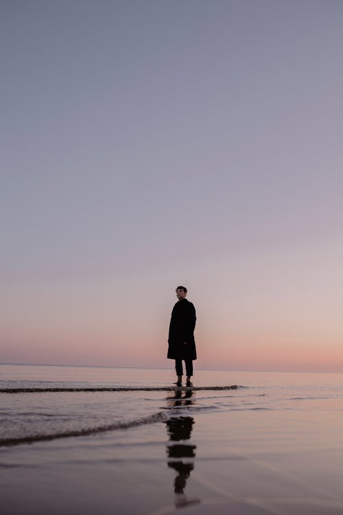 Man Standing on Sea Shore at Dusk