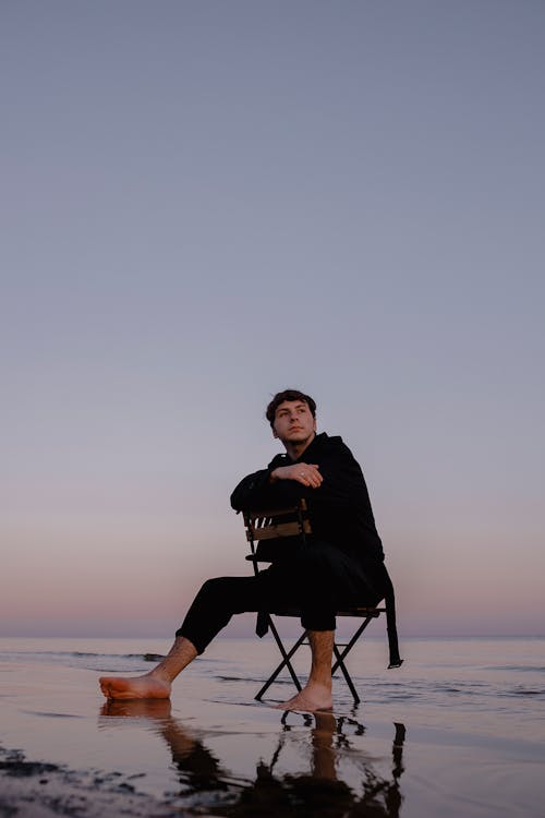 Man on Chair on Sea Shore at Dusk