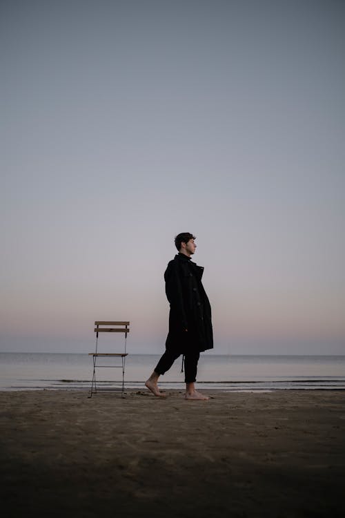 Man Walking near Chair on Beach