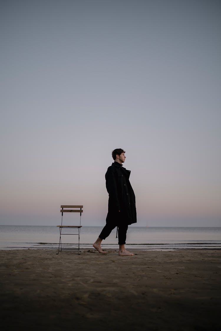 Man Walking Near Chair On Beach